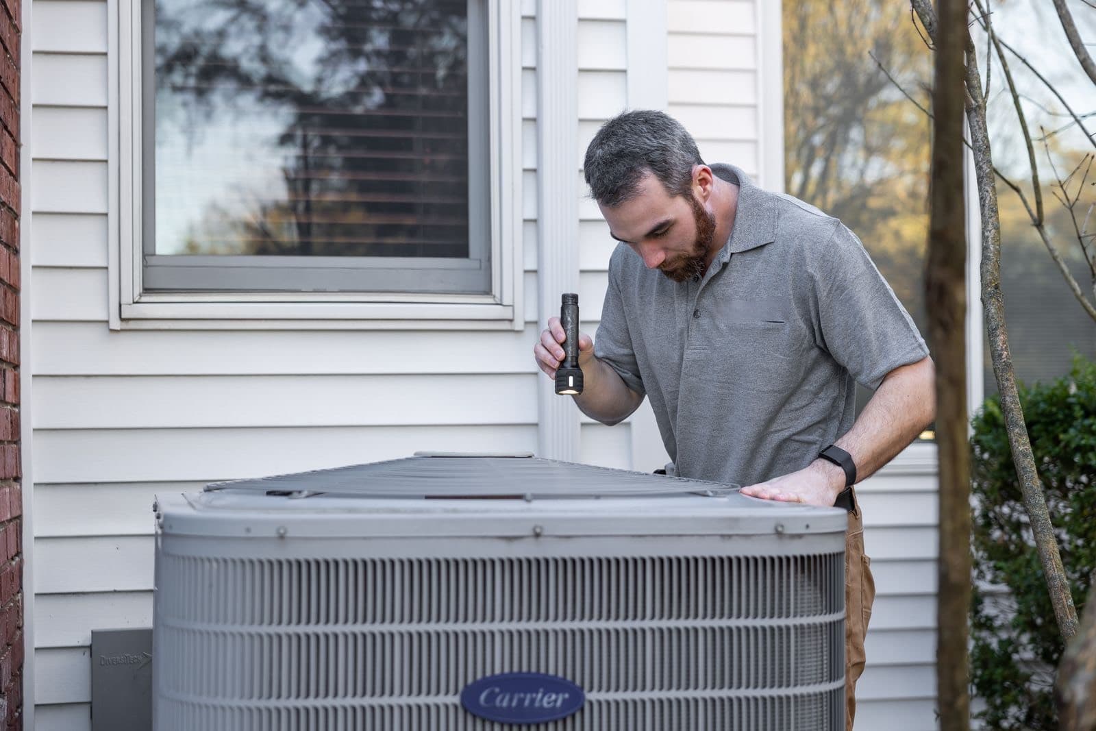 Technician inspecting an AC unit, Badger Heating & Air demo site