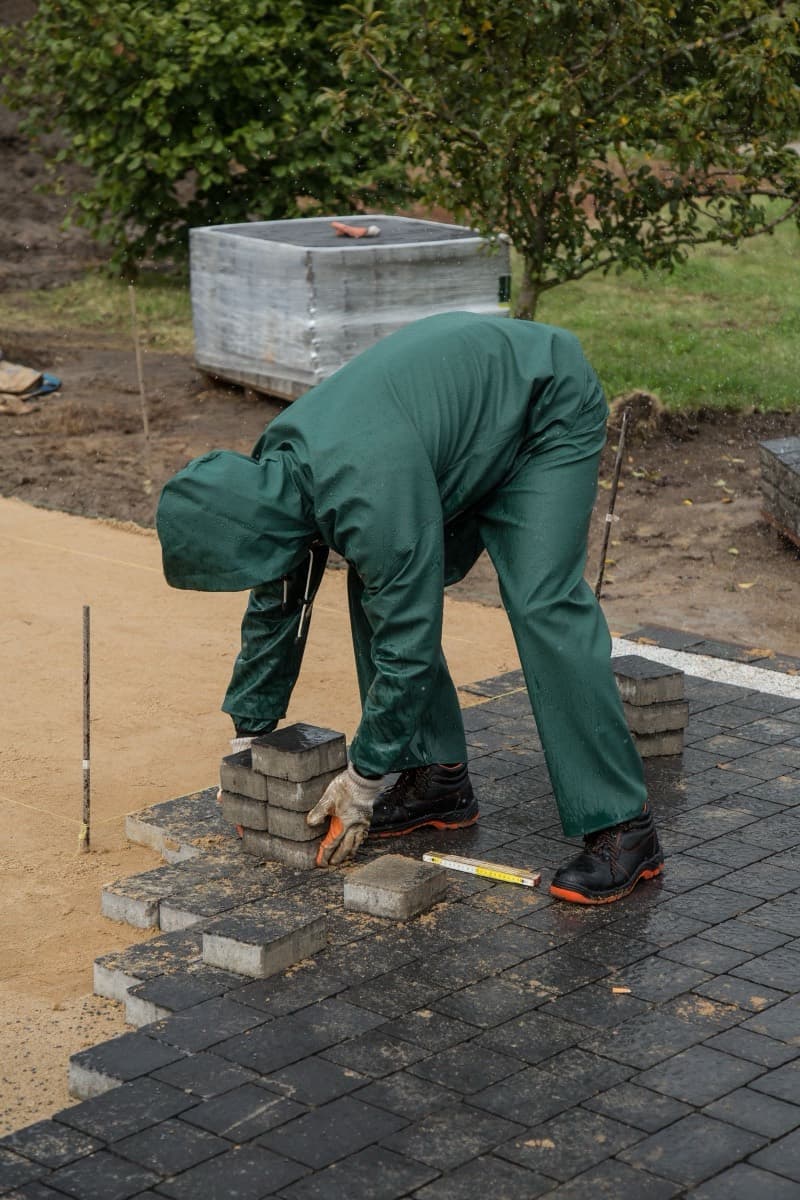 Crew member laying interlocking pavers on a prepared base