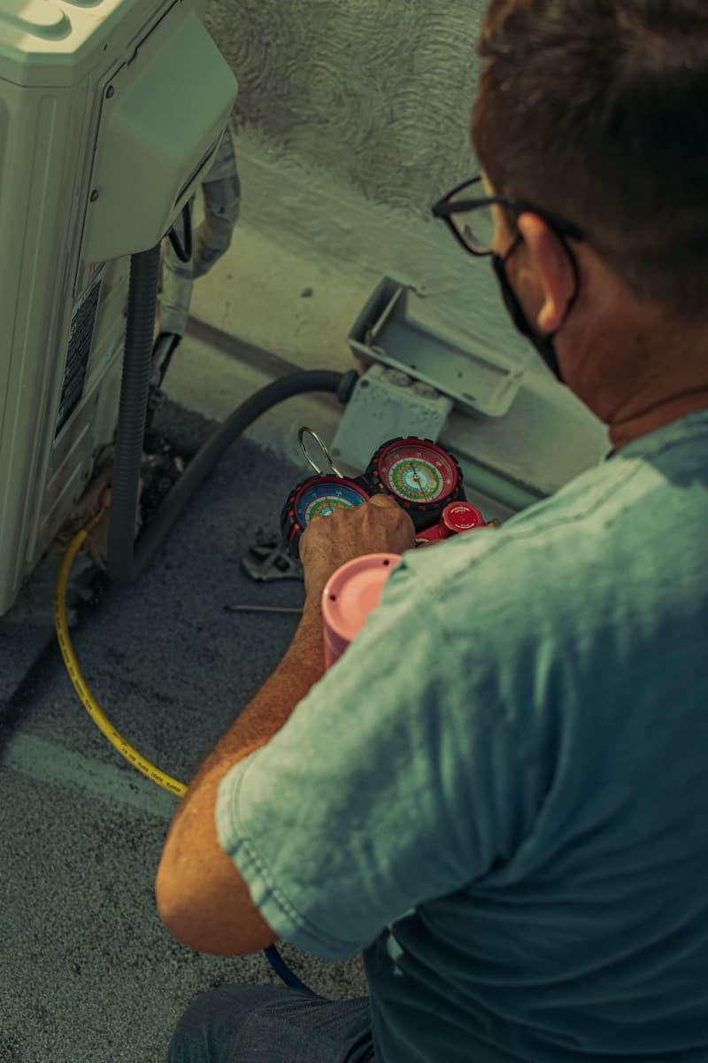 Technician reading manifold gauges during refrigerant service