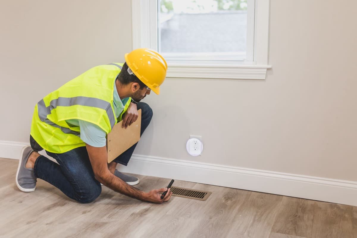 Inspector checking a floor supply vent in a home